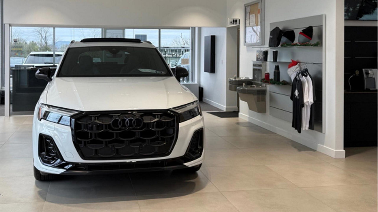 Front view of a white Audi parked in the dealership showroom 