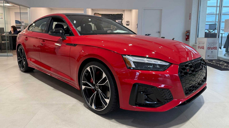 Right side profile of a red Audi in a dealership showroom