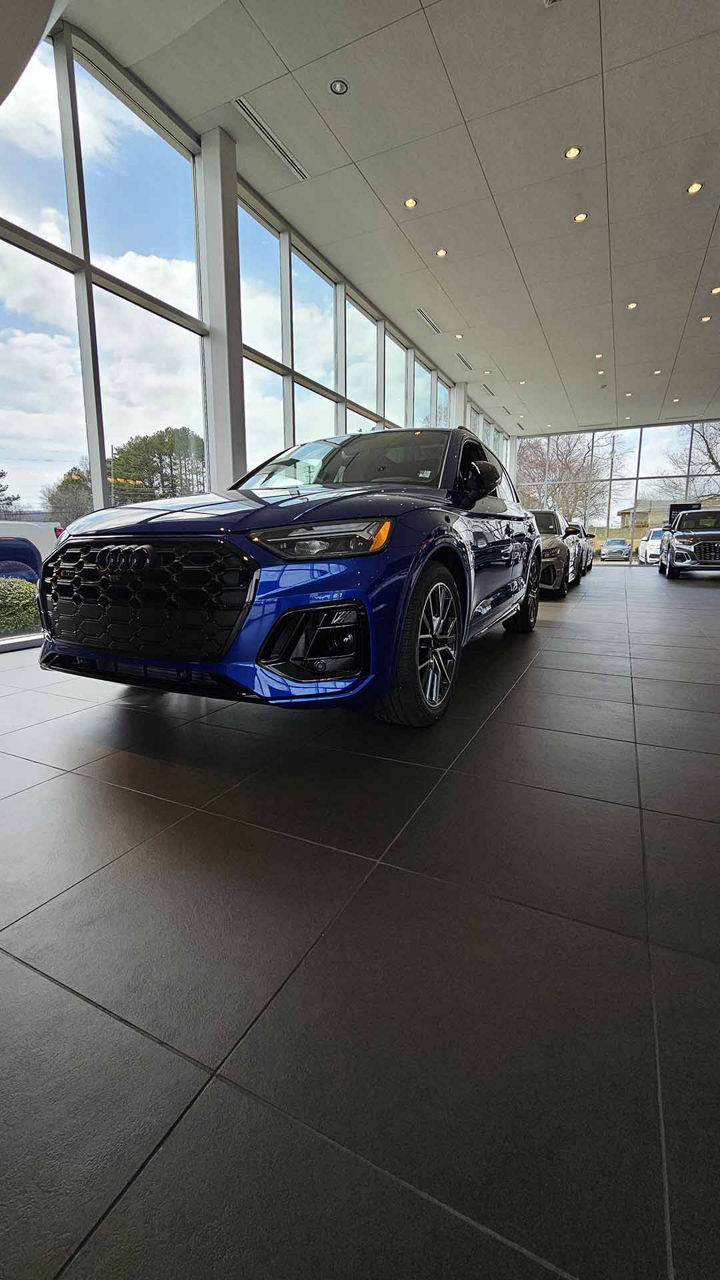 Front profile view of an Audi vehicle parked in the showroom. 