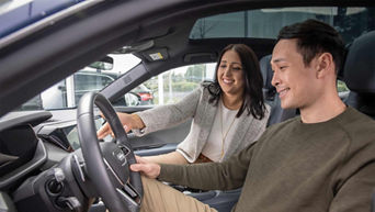 Audi sales specialist sitting next to customer in an Audi and explaining the vehicle features.