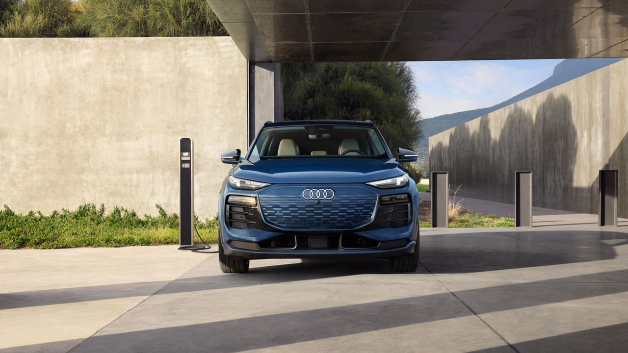 Image from the front of a blue 2025 Audi Q6 e-tron parked at an electric charging station