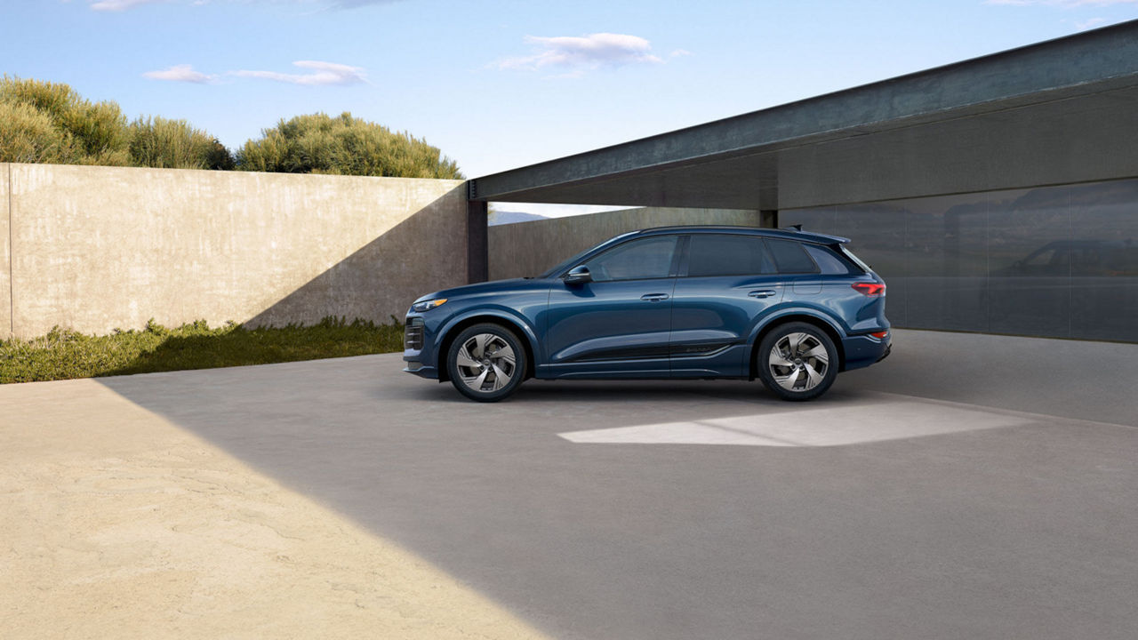Profile view image of a blue 2025 Audi Q6 e-tron parked next to a building