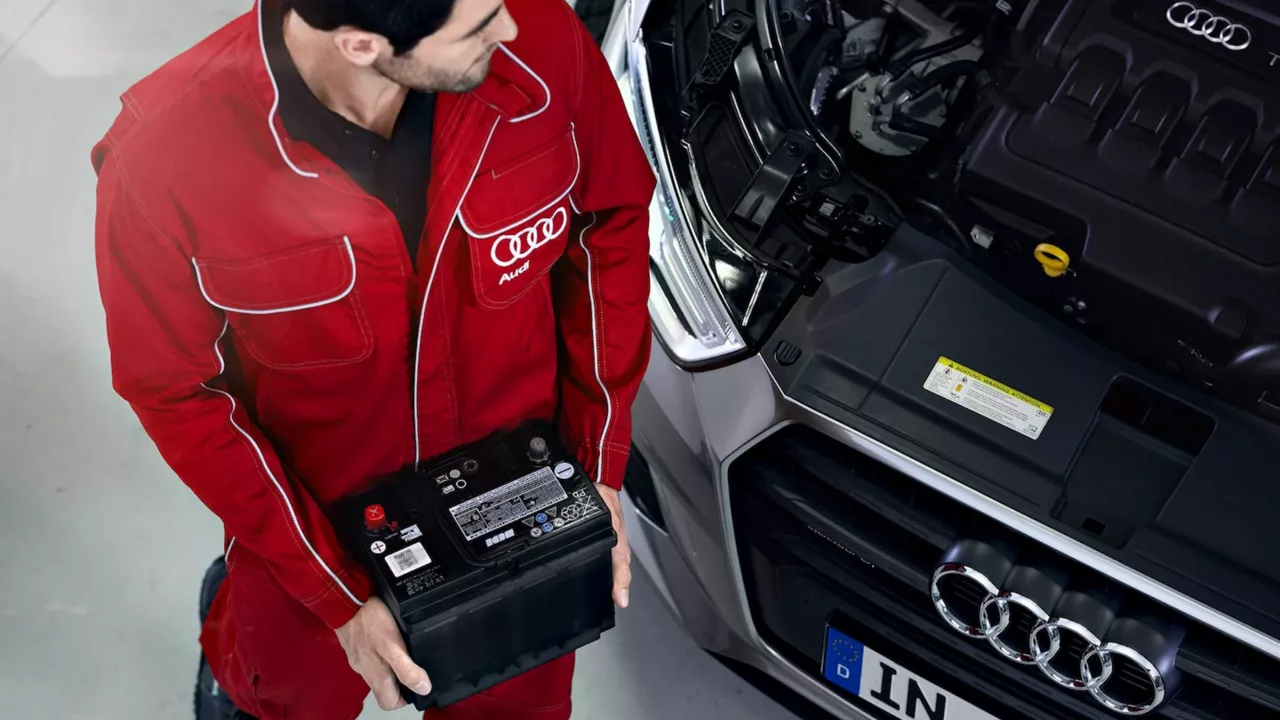 Birds eye view of an Audi service technician changing a battery in a vehicle.