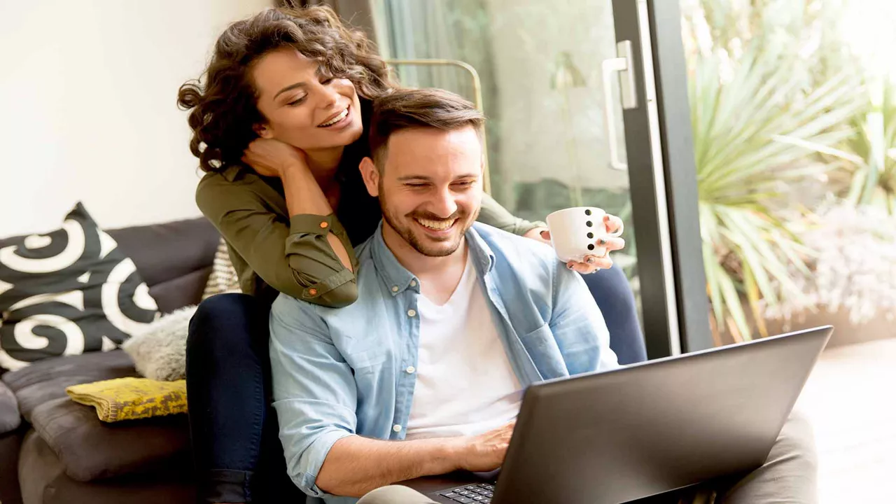 Young couple sitting on floor using a notebook computer.