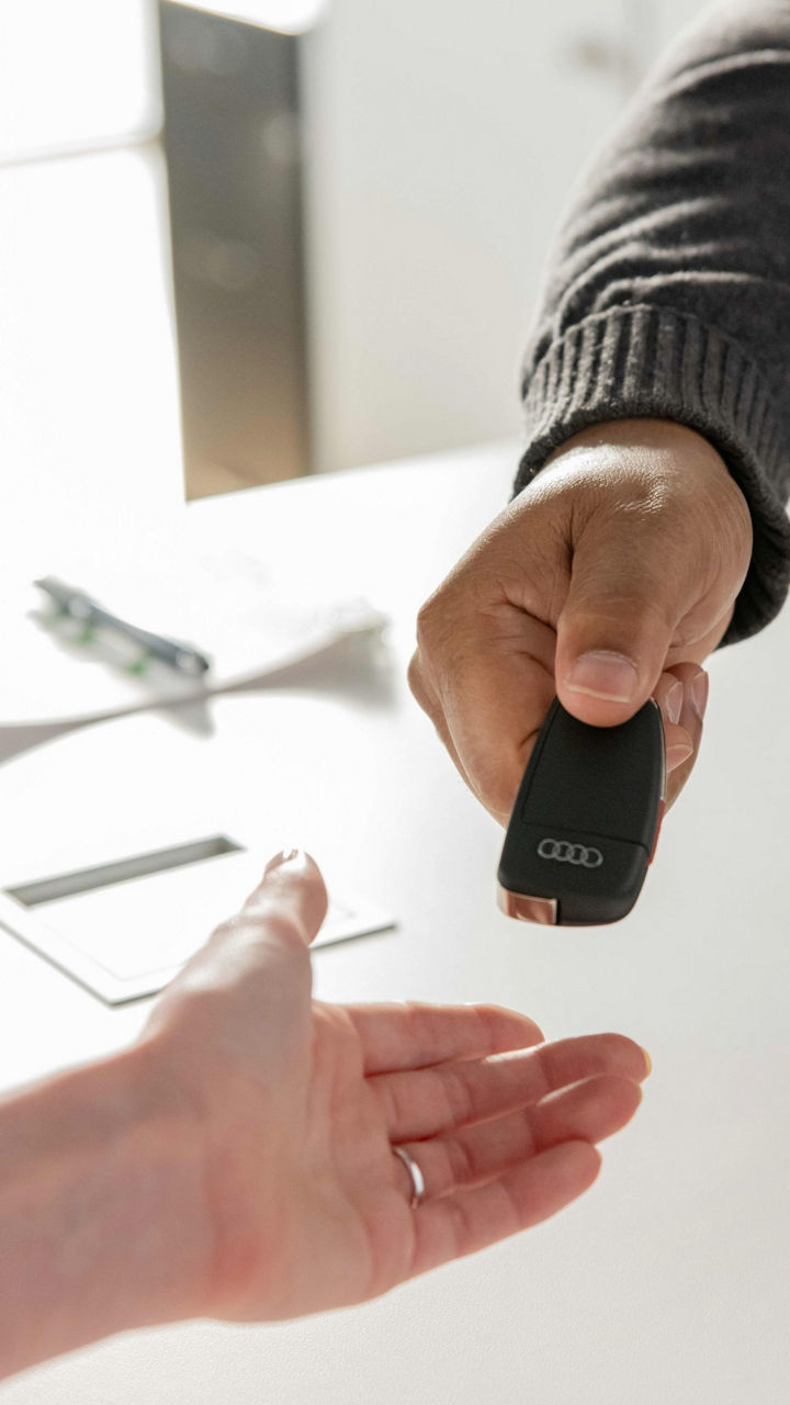 An Audi sales representative handing keys to a customer.