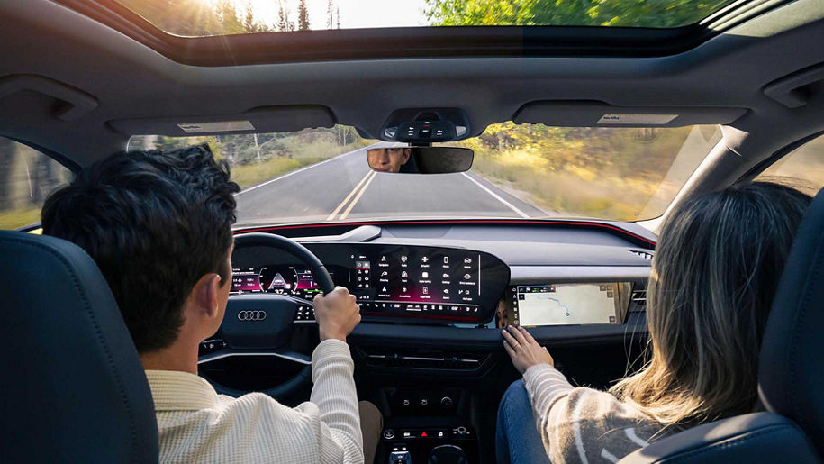 Two individuals driving an audi vehicle.