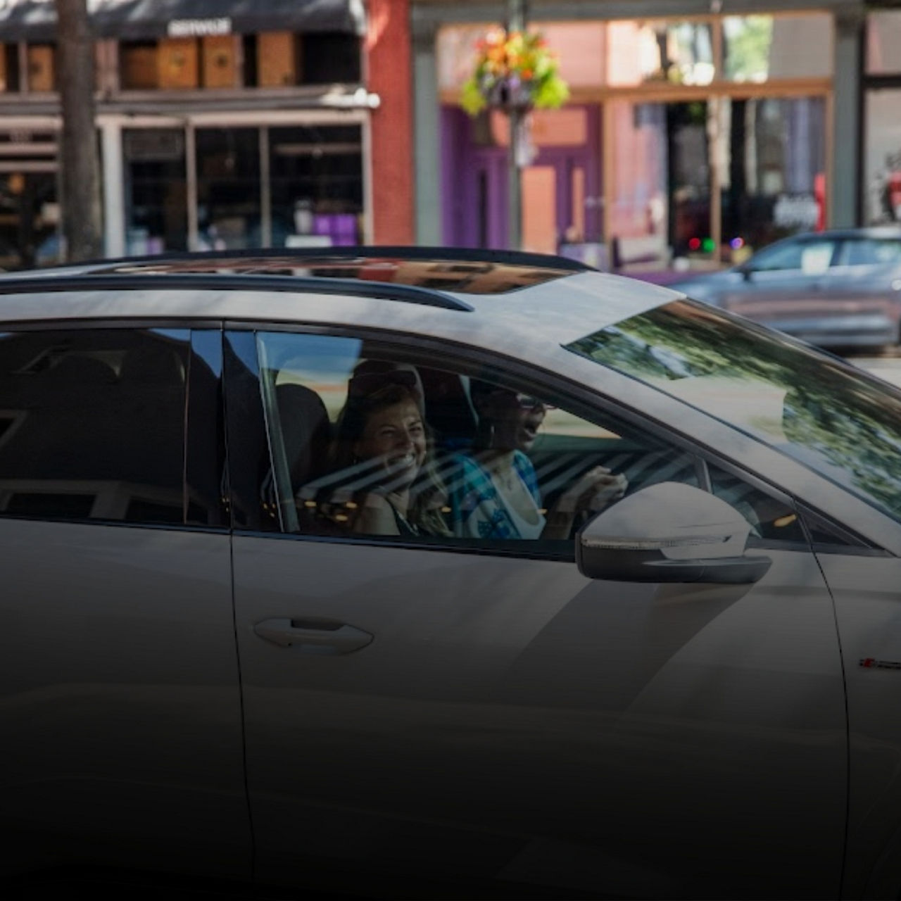 Two women sitting in the front seats of a parked Audi, viewed from outside the car. 