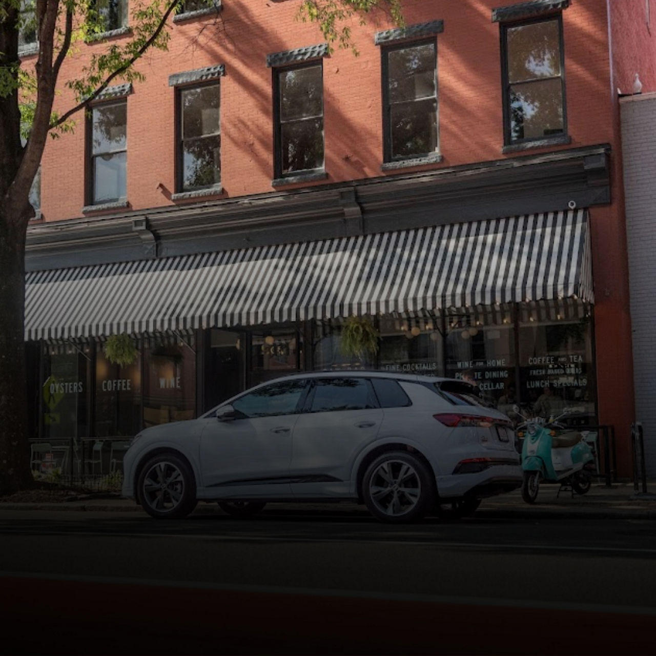Side view of a white Audi SUV parked on the side of the street. 