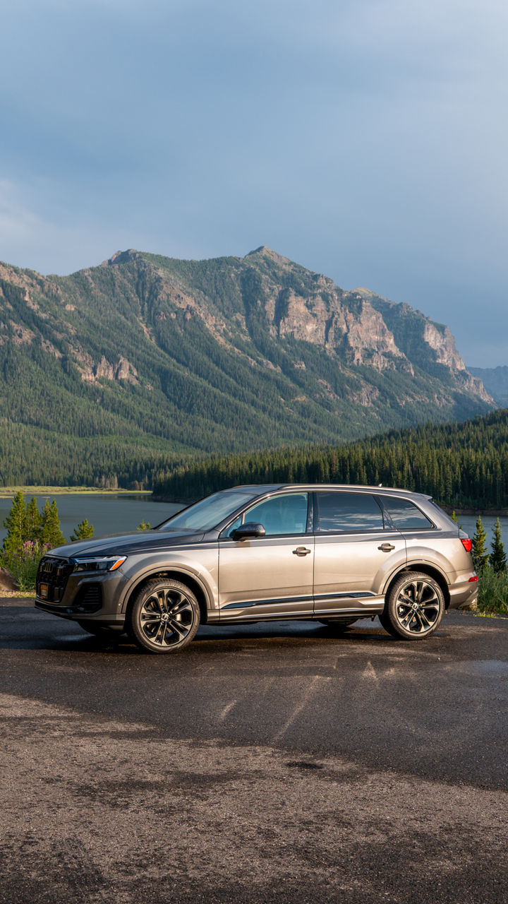 Audi vehicles parked near mountains.