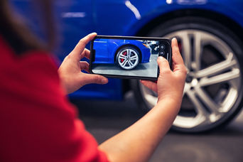 Service advisor taking a picture of a vehicles wheel.