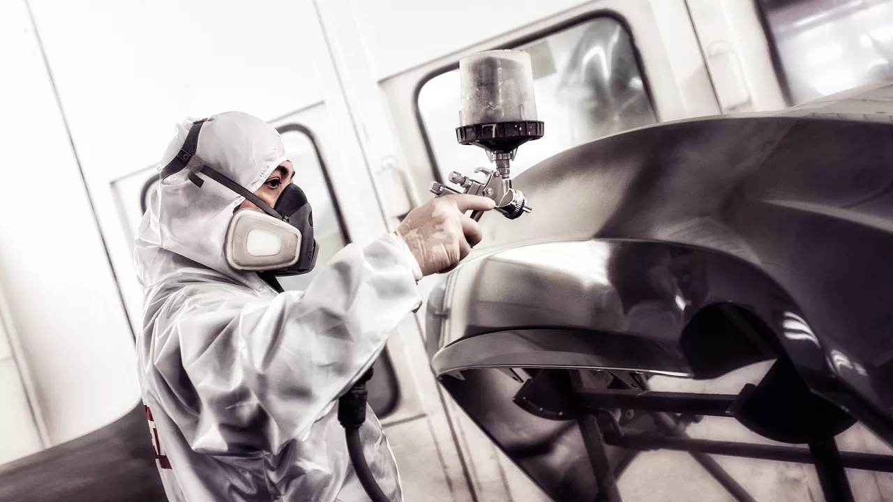 Prestige Imports Collision Center technician painting a vehicle bumper