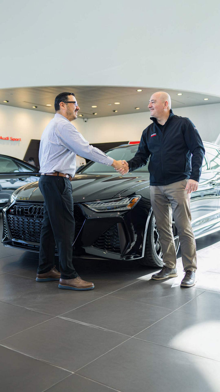Image of Audi employee greeting man. 