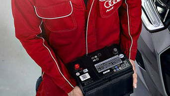 Service technician holding car battery.