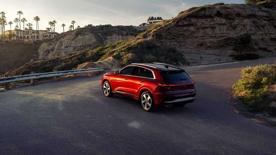 Red Audi driving up winding road at sunset