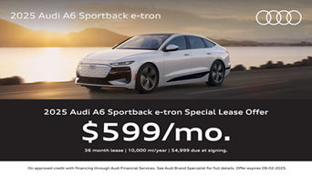A white Audi A6 e-tron driving near the water with a sunset.