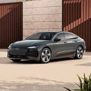 Front 3/4 view of a grey Audi A6 Sportback e-tron parked outside a modern building 