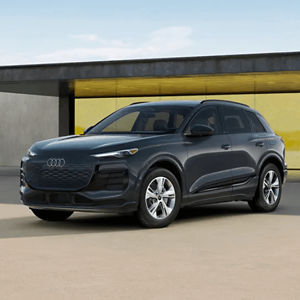 Front 3/4 view of a black Audi Q6 e-tron parked outside a modern building 