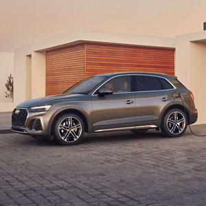 Side view of a grey Audi Q5 Plug-in Hybrid parked outside a modern building