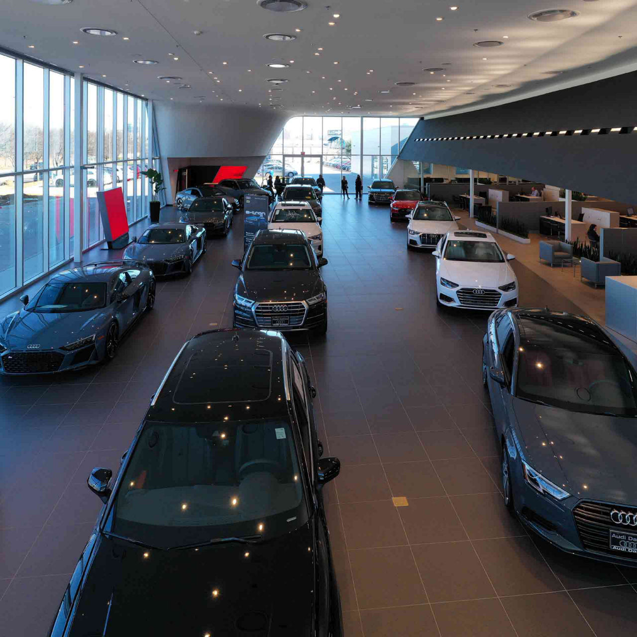 Aerial view of a fleet of vehicles inside an Audi dealership.