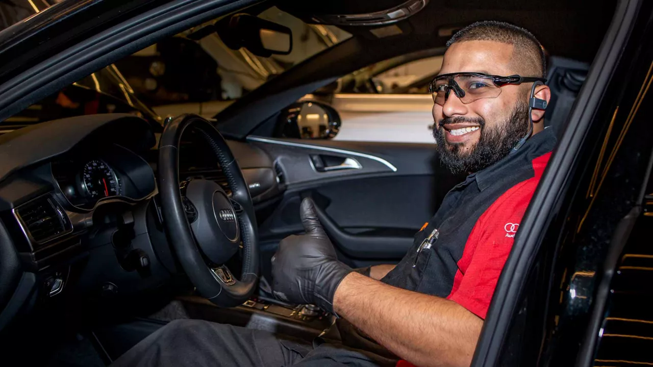 Side view of a technician in the front seat of an Audi vehicle. 