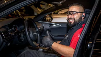 Side view of a technician in the front seat of an Audi vehicle. 