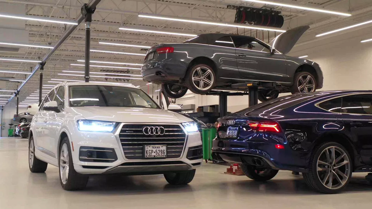 Several Audi vehicles inside a dealership service station. 