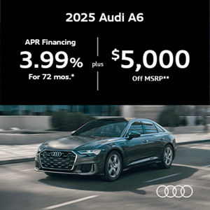 Audi A6 driving along road next to sidewalk and building
