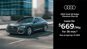 Audi A6 driving past a sidewalk and building