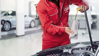 Service technician servicing vehicle with hood open.