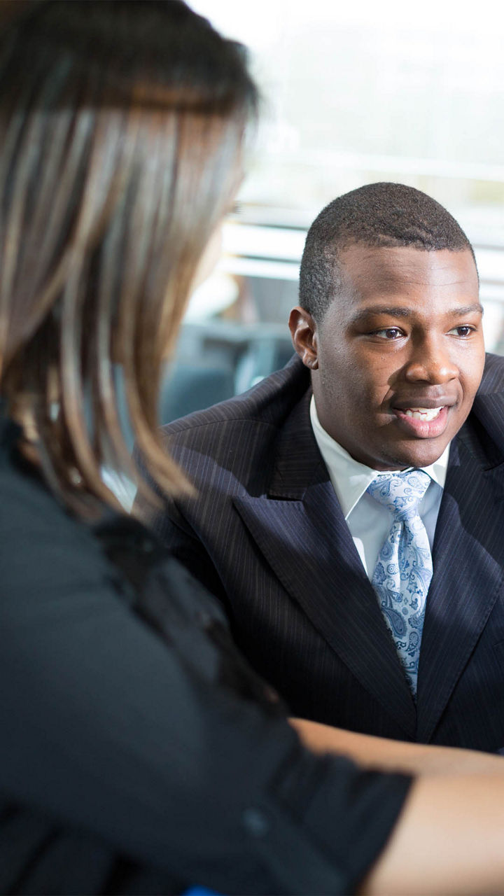 Sales Associate sharing Audi technology with a customer in a vehicle available for sale.