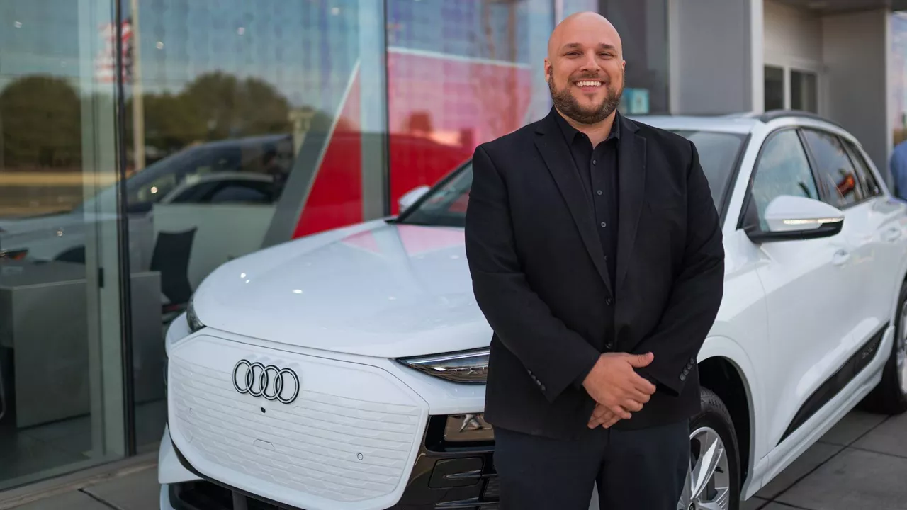 Man standing in front of Audi vehicle. 