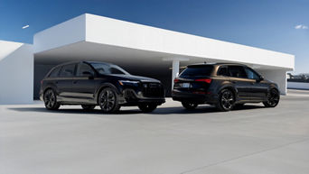 Two 2026 Audi Q7 models parked next to each other to show dimensions against a modern building