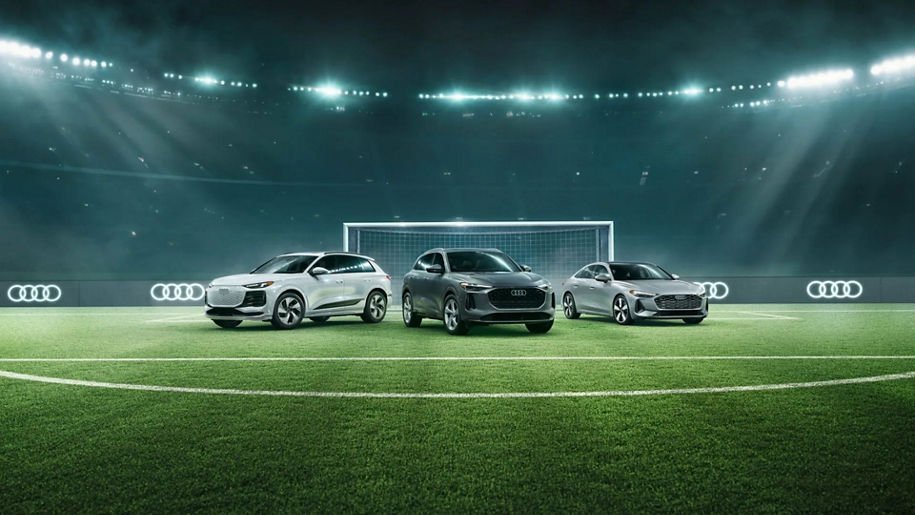 Three Audi vehicles parked on a soccer field.