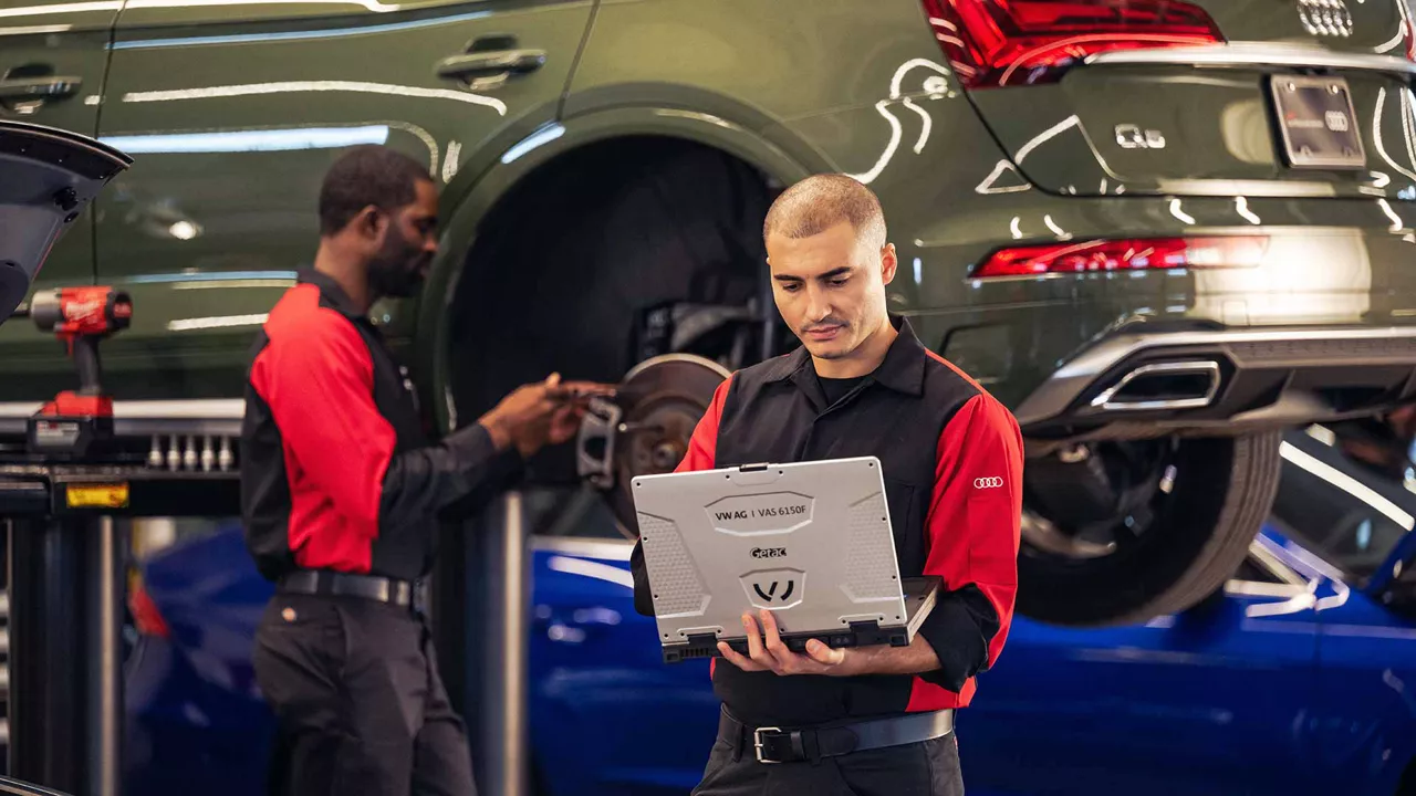 Two Audi Technicians working on an Audi Vehicle on the car lift.