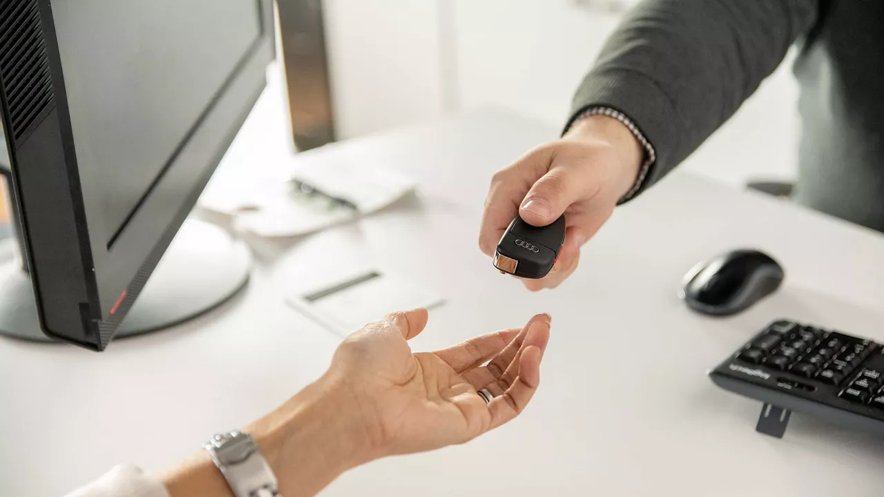 Audi employee handing a set of car keys to a customer.