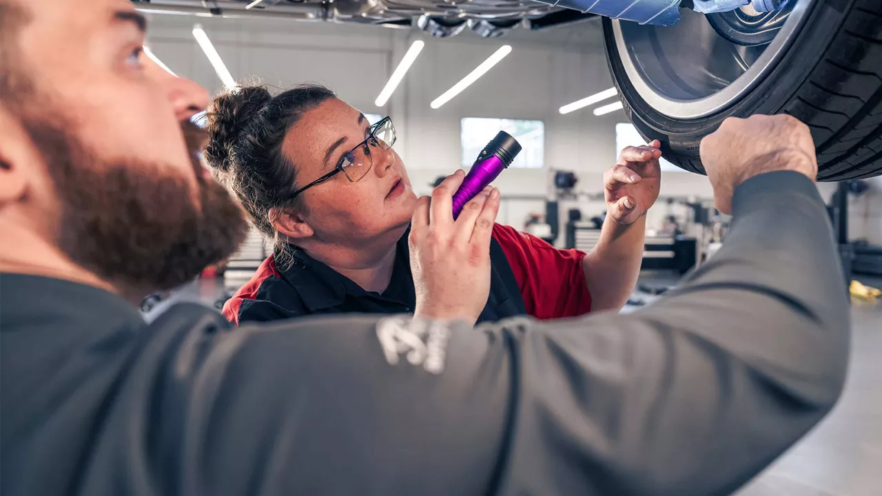 Technicians looking at tire with flashlight