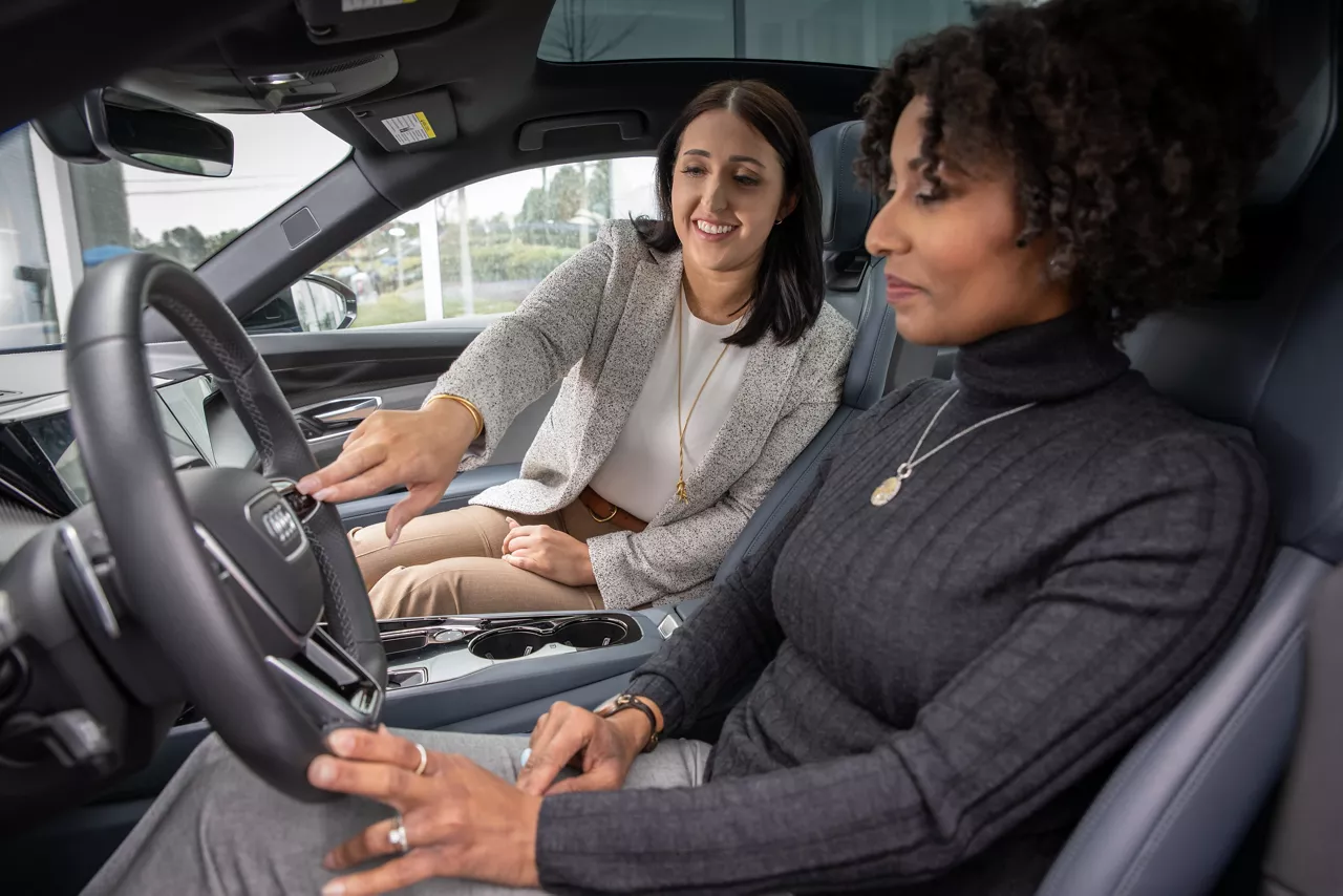 Audi sales specialist sitting next to customer in an Audi and explaining the vehicle features. 