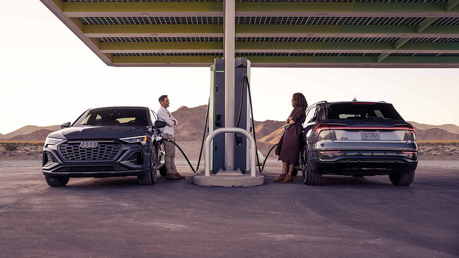 Two people facing each other while charging their vehicles