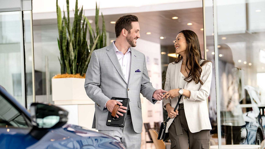 An Audi dealer passing over car keys to a customer.